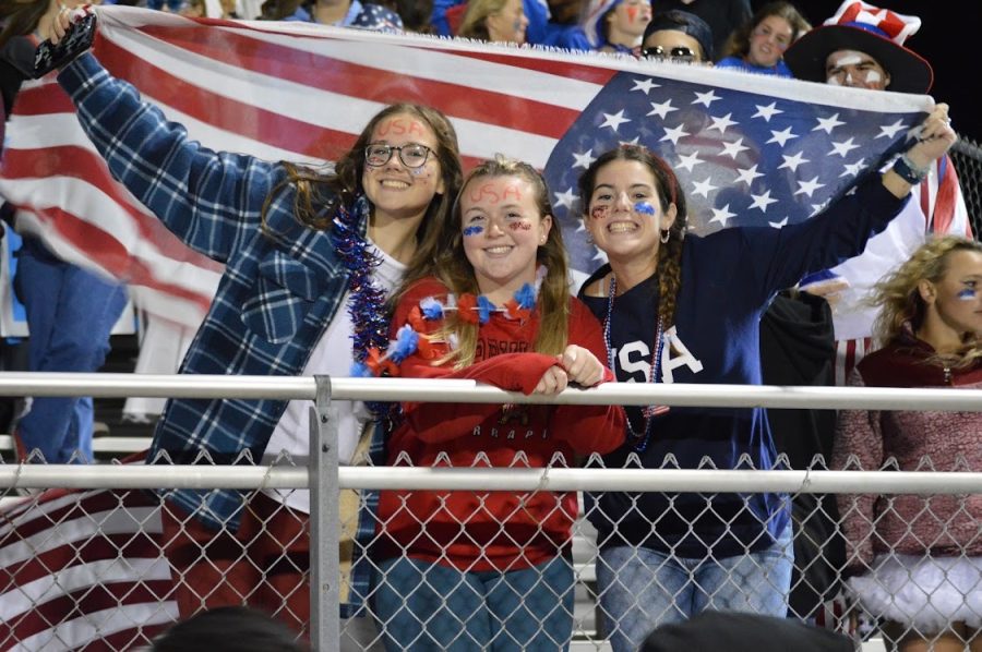 Seniors Grace Nichols, Renee Fohner, and Deanna Dodson hold up a flag at the USA game. 