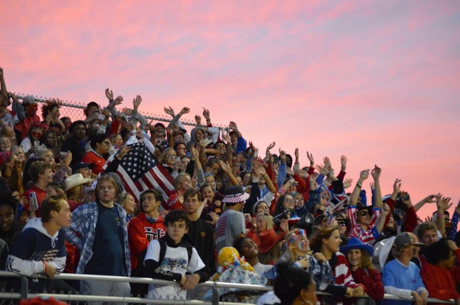 The sun sets behind the student section, dressed in red, white, and blue during the Parkside game. 