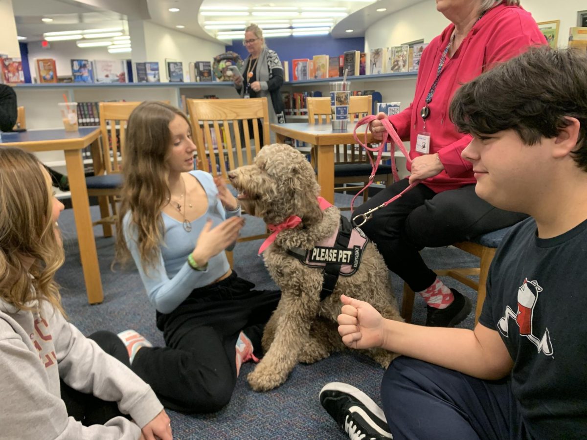 To ease test-taking anxiety during Final Exams on Jan. 29-30, the Guidance office brought in several therapy dogs from Pets on Wheels, including Gracey the Labradoodle, pictured here with junior Issy Mitchell.